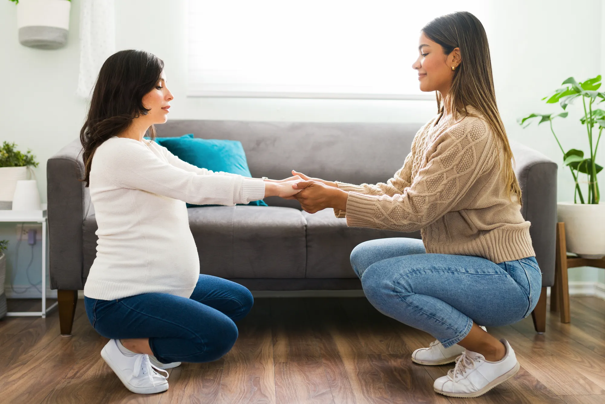 A midwife sitting with a client, holding her hands.